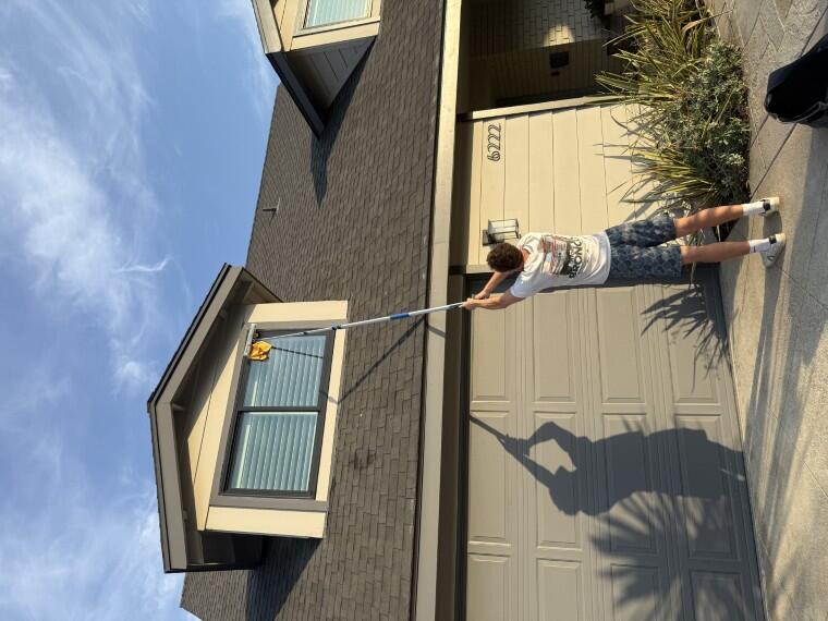 Technician cleaning a dormer window with an extension pole