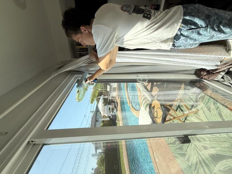 Technician cleaning an interior slider with pool view